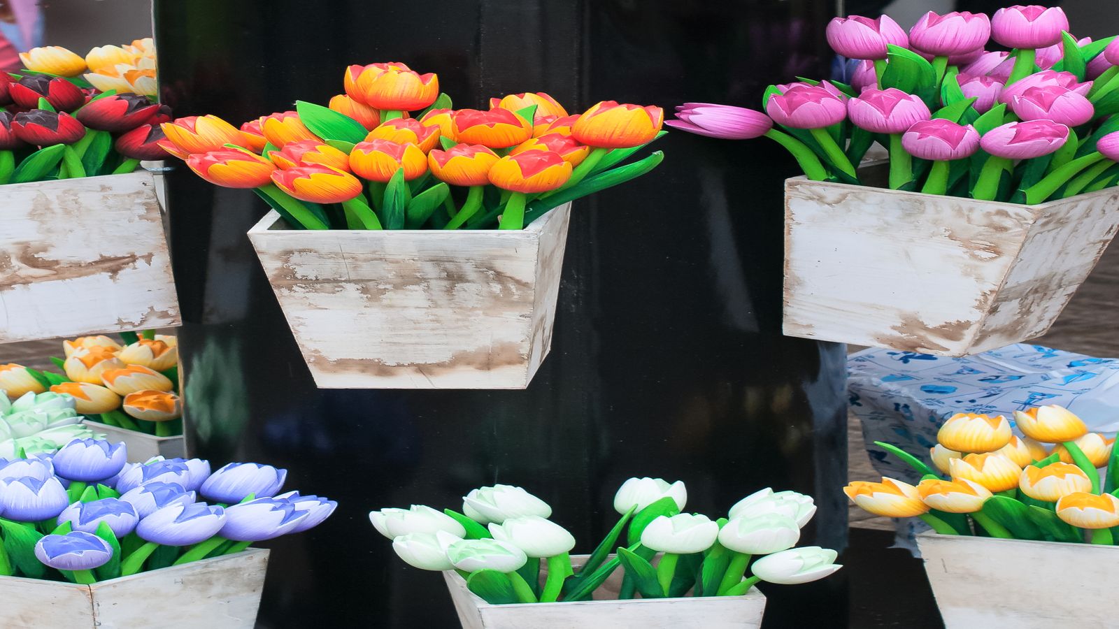 Bunches of freshly cut tulips in buckets at a market stall with a Bitcoin-accepted sign