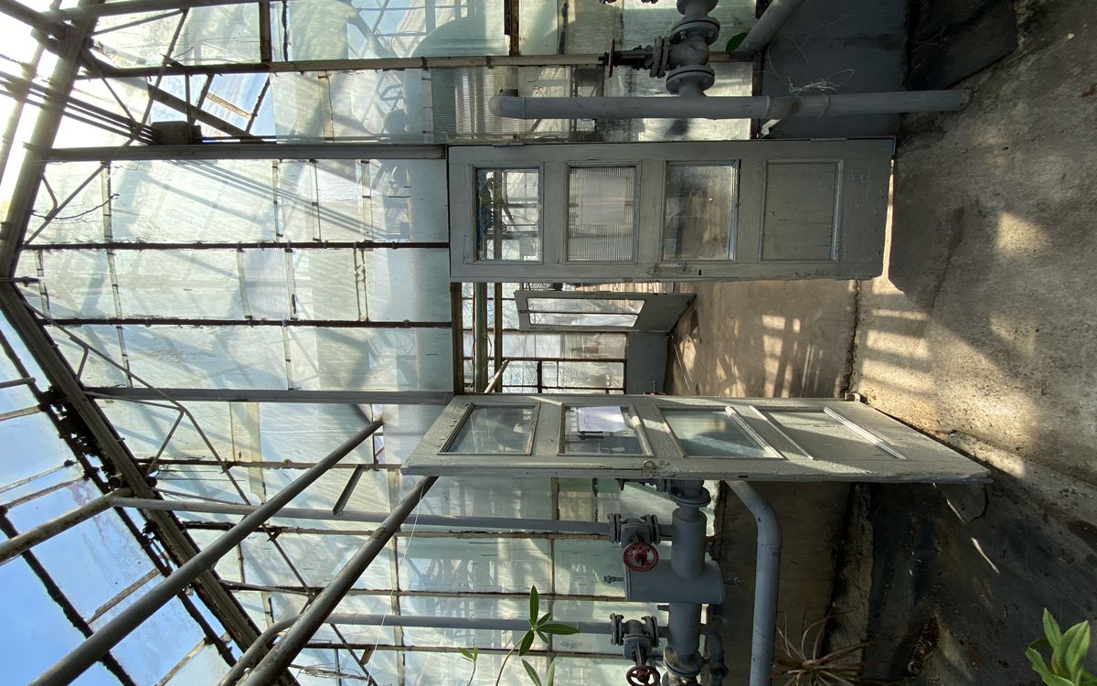 Mining rig enclosure with ducting leading to a greenhouse structure visible through an open door