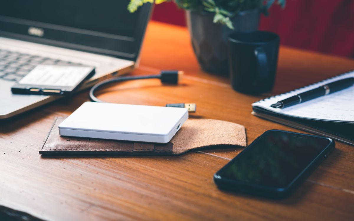 Clean workspace with a hardware wallet, a backup card, and a pen on a wooden desk